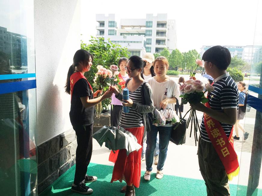 说明: D:\2019年新闻\图书在4.23世界读书日期间开展 捧书卷 赠你鲜花活动\在图书馆门口举行赠花活动.jpg